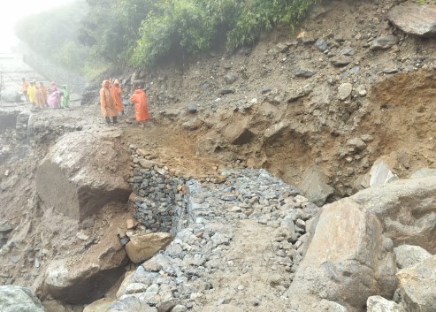 क्षतिग्रस्त मार्ग को ठीक करने में जुटे मजदूरों पर खराब मौसम की मार